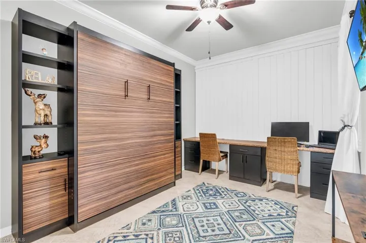 Home office featuring ceiling fan, built in features, crown molding, and wooden walls