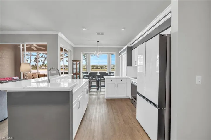 Kitchen with a center island, crown molding, white cabinetry, stainless steel electric stove, and white refrigerator