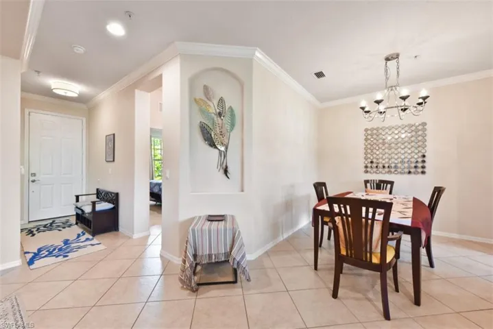Tiled dining space with a notable chandelier and crown molding