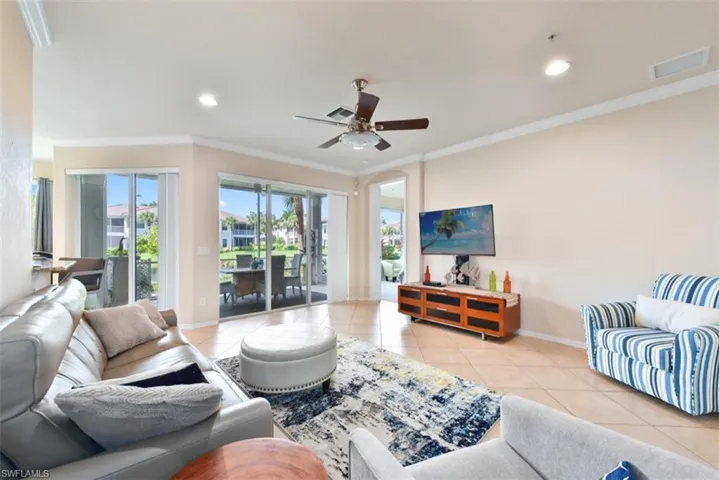Living room with ceiling fan, ornamental molding, and light tile patterned floors