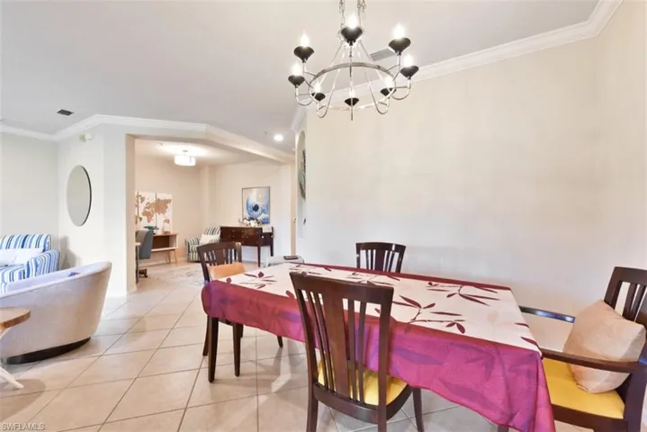 Tiled dining room featuring crown molding and a notable chandelier