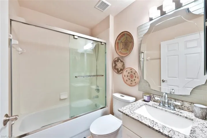 Full bathroom featuring toilet, shower / bath combination with glass door, and vanity