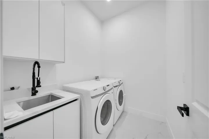 Laundry area with washer and clothes dryer, light marble finish flooring, cabinet space, and recessed lighting