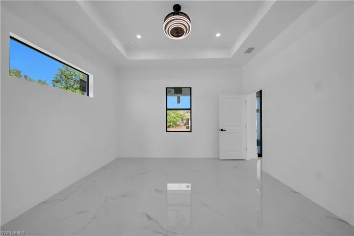 Spare room featuring recessed lighting, a tray ceiling, and light marble finish floors