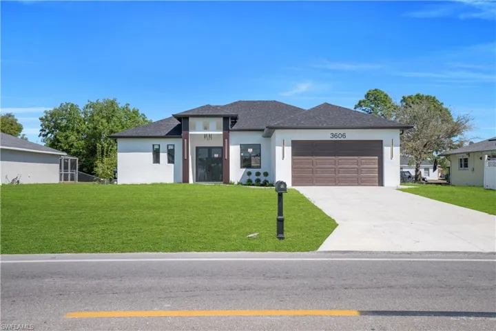 Prairie-style home with a front yard, an attached garage, driveway, stucco siding, and roof with shingles