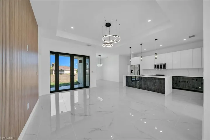 Unfurnished living room with a tray ceiling, recessed lighting, and light marble finish floors