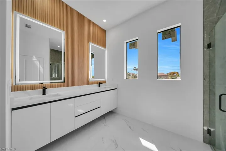 Full bathroom with double vanity, a shower stall, recessed lighting, and light marble finish flooring