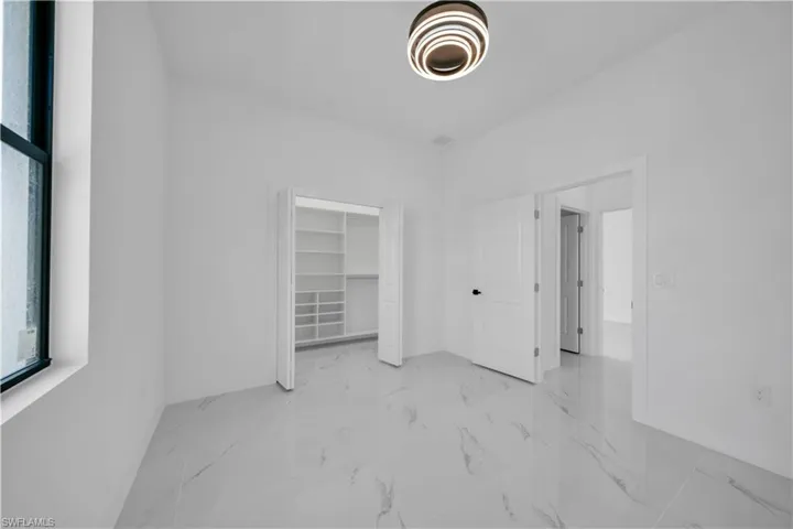 Unfurnished bedroom with a spacious closet and baseboards
