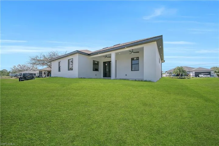 Back of house featuring stucco siding, a yard, a patio, and ceiling fan