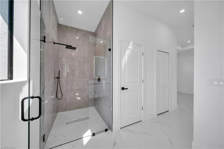 Bathroom with a marble finish shower, recessed lighting, and light marble finish floors