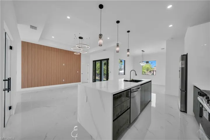 Kitchen featuring modern cabinets, a spacious island, light stone countertops, pendant lighting, and a raised ceiling