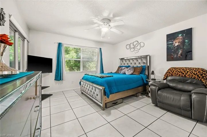 Bedroom with a textured ceiling, light tiled floors, and a ceiling fan