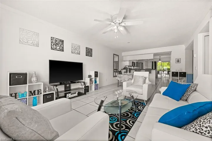 Living room with tile patterned flooring, a ceiling fan, and crown molding