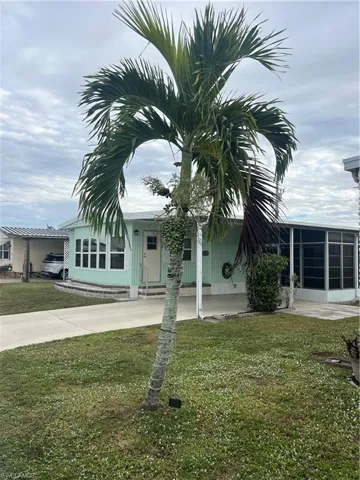 View of front of property featuring a sunroom, a front lawn, a patio, and driveway