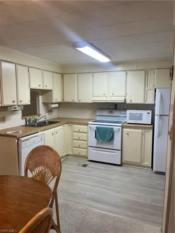 Kitchen with white stove, refrigerator, light wood-type flooring, dishwashing machine, and crown molding