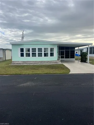 Manufactured / mobile home with a front yard, a carport, and concrete driveway