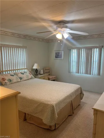 Bedroom featuring multiple windows, light colored carpet, and ceiling fan