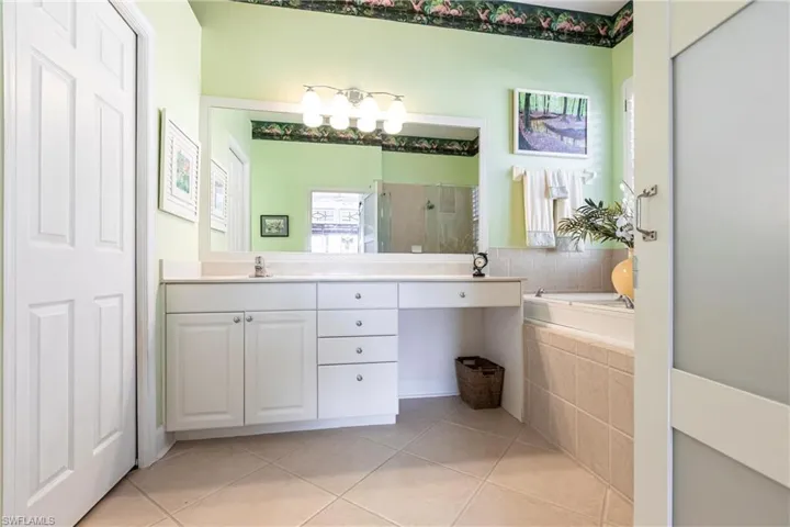 Bathroom with a stall shower, light tile patterned floors, double vanity, and a garden tub