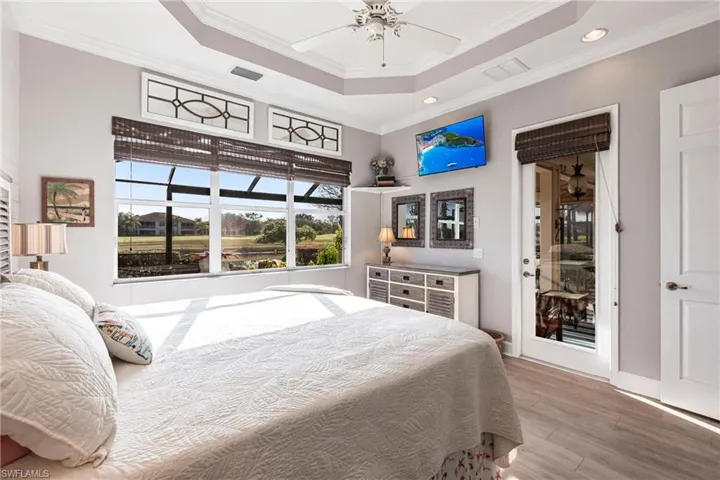 Bedroom with a tray ceiling, ornamental molding, light wood-style floors, a ceiling fan, and recessed lighting