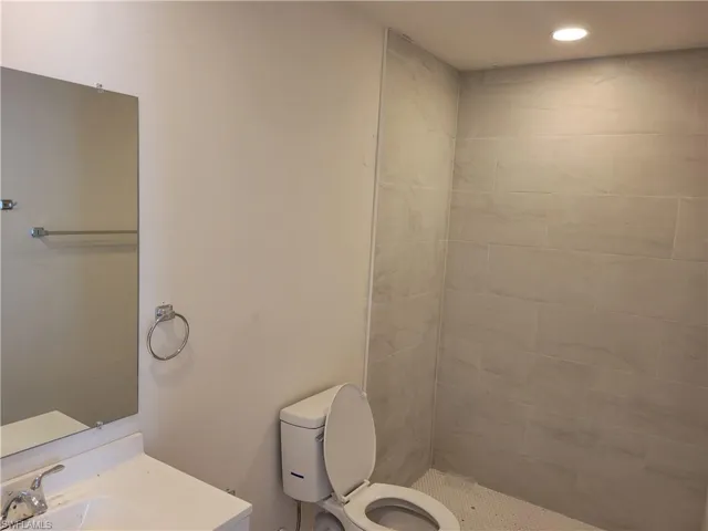 Bathroom with a tile shower, sink, and toilet