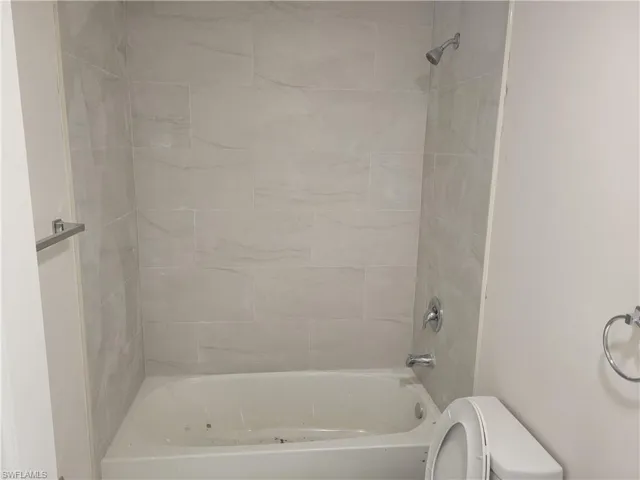 Bathroom with tiled shower / bath and toilet