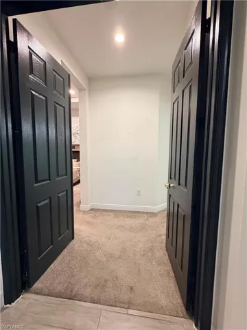 Entryway featuring a tile-to-carpet transition, dark paneled doors, and recessed lighting
