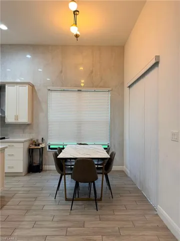 Dining area with a sophisticated tile accent wall, wood-finish flooring, and recessed ceiling lighting