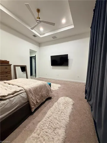 Carpeted room featuring a tray ceiling with recessed lighting and a ceiling fan