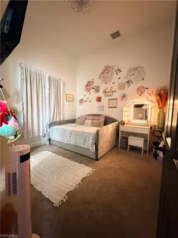 Carpeted room with a window featuring light-colored drapes, a built-in recessed light fixture, and a built-in ceiling vent