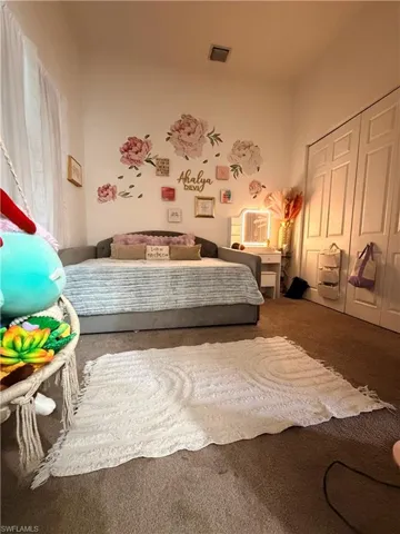 Spacious room featuring carpeted flooring, white walls, and a built-in closet with bi-fold doors