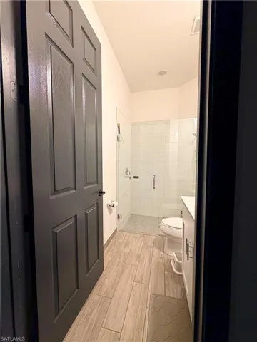 Bathroom featuring a frameless glass shower enclosure, a white toilet, and a vanity with a white countertop