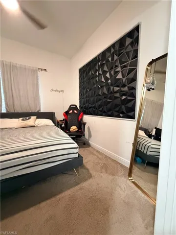 Carpeted room featuring a ceiling fan, a framed geometric wall art installation, and a full-length mirror
