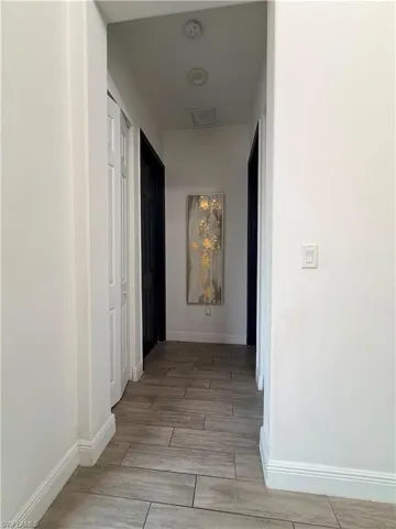 Hallway featuring plank-style tile flooring, white baseboards, and recessed lighting