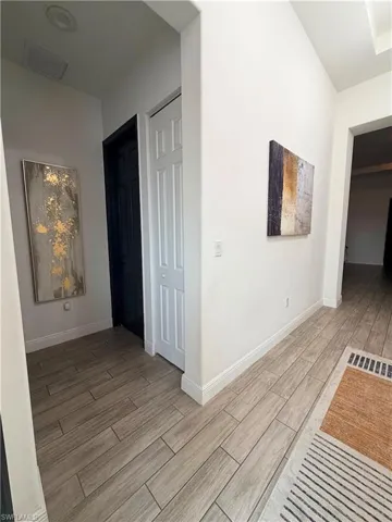 Hallway featuring plank-style tile flooring and a white baseboard trim