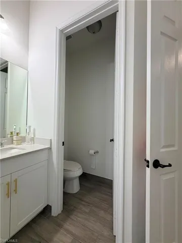Bathroom vanity featuring a white quartz countertop, undermount sink, and shaker-style cabinetry with gold-tone hardware
