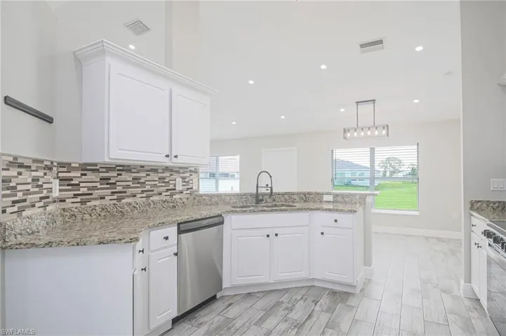 Kitchen with appliances with stainless steel finishes, white cabinetry, a healthy amount of sunlight, and sink
