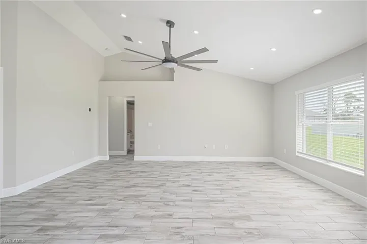 Spare room with lofted ceiling, ceiling fan, and light hardwood / wood-style floors