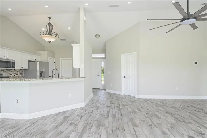 Kitchen featuring light wood-type flooring, ceiling fan, high vaulted ceiling, and stainless steel appliances