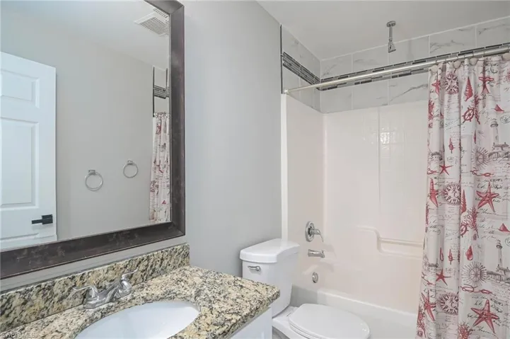 Full bathroom featuring shower / bathtub combination with curtain, toilet, and vanity