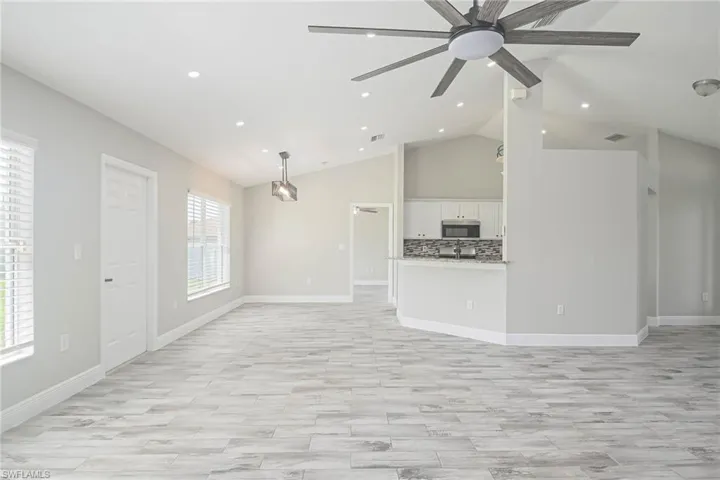 Unfurnished living room with lofted ceiling, ceiling fan, and light hardwood / wood-style flooring