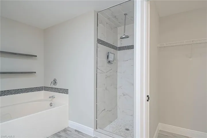 Bathroom featuring shower with separate bathtub and wood-type flooring