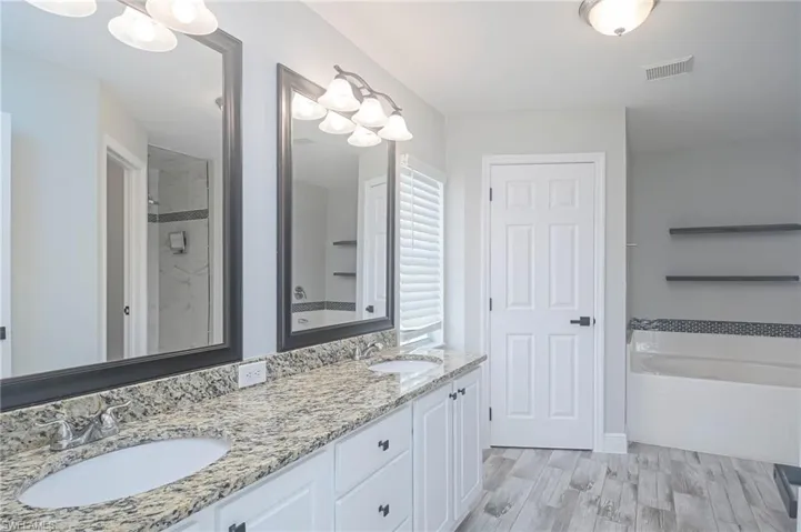 Bathroom featuring vanity, hardwood / wood-style flooring, and shower with separate bathtub