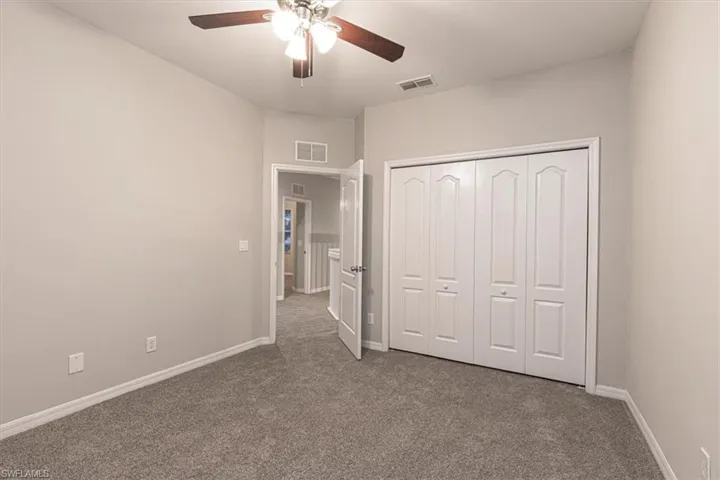 Unfurnished bedroom featuring dark colored carpet, ceiling fan, and a closet