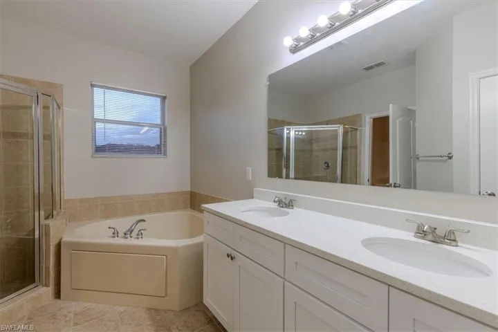 Full bathroom with double vanity, a stall shower, a garden tub, and light tile patterned flooring