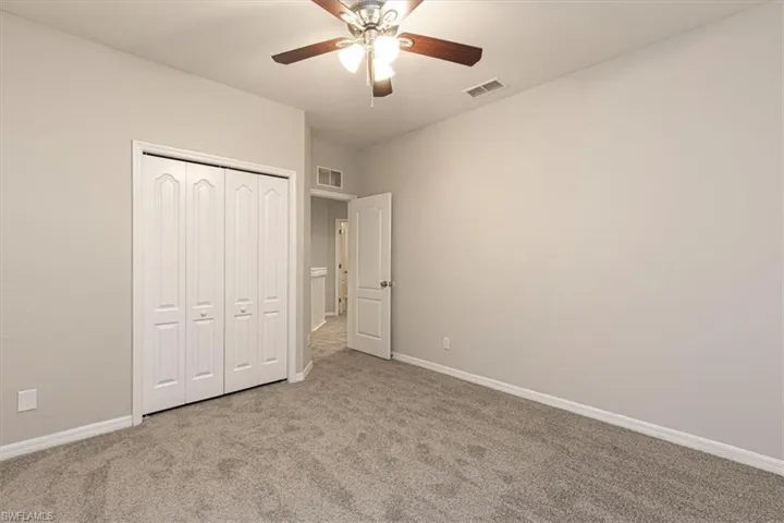 Unfurnished bedroom featuring light colored carpet, a ceiling fan, and a closet