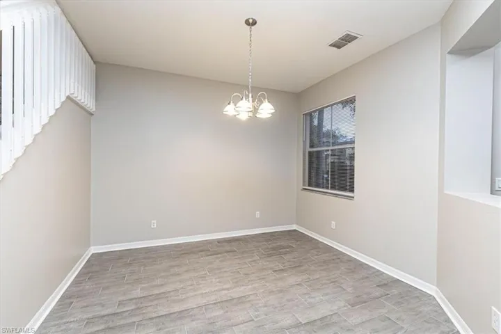 Empty room with light wood-style floors and a chandelier