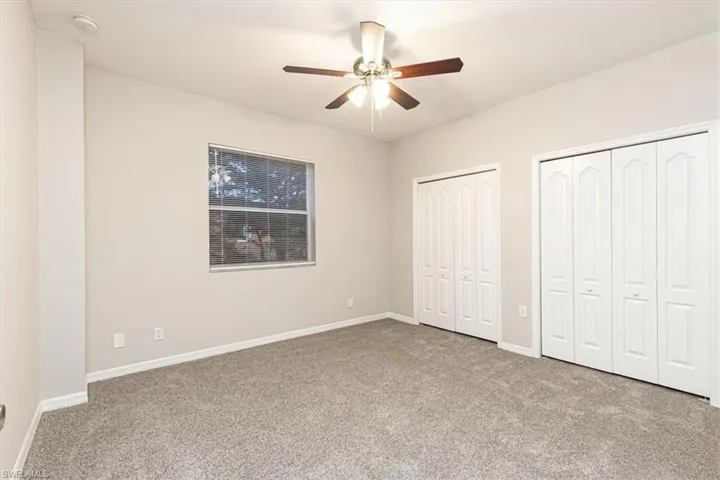 Unfurnished bedroom with two closets, light carpet, and ceiling fan