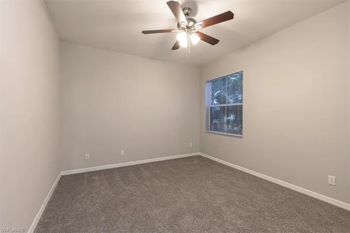Carpeted empty room featuring baseboards and ceiling fan