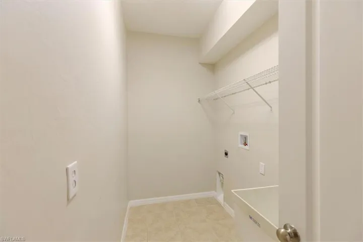 Washroom featuring hookup for a washing machine, electric dryer hookup, and light tile patterned flooring