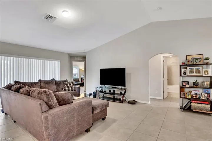 Living room with lofted ceiling, arched walkways, and light tile patterned floors